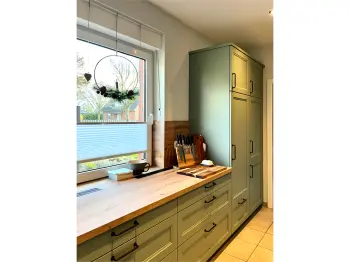 Salbeigrüne Küchenzeile vor einem Fenster