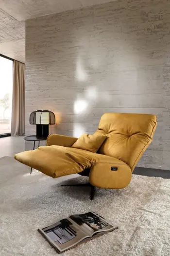 Gelber Relaxsessel aus Leder mit ausgeklappter Fußlehne und zurückgelehnter Rückenlehne.
