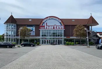 Haupteingang des Möbelhauses Wohnwelt von Harten mit einladender Glasfassade und Parkplätzen davor.