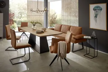 Moderner Esstisch aus Massivholz Eiche mit schwarzem Fußgestell, um den Stühle und eine Sitzbank mit Lederbezug in Cognac stehen.