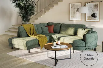 Grünes Ecksofa in hellem Raum mit rudem Beistelltisch und Garantievermerk. 