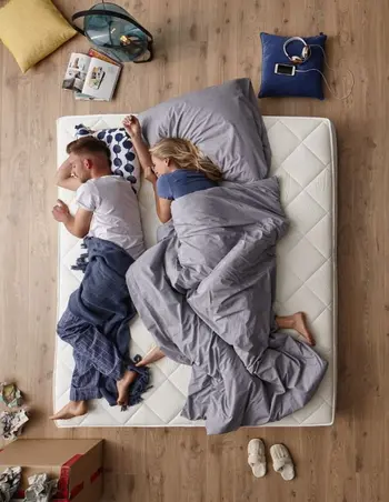 Frau und Mann liegen seitlich auf einer Matratze.