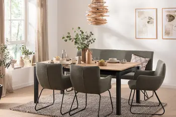 Esstisch mit Holzplatte auf schwarzem Metallgestell mit grüner Sitzbank und grünen Schalenstühlen in Boucle um den Tisch.