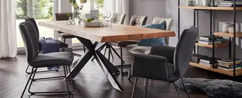 Esstisch aus Massivholz mit schwarzem Spinnenfußgestell, um den mehrere Stühle mit und ohne Armlehne in Grautönen stehen.