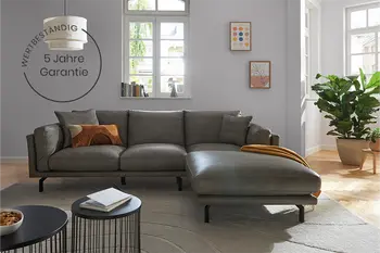 Graues Ledersofa mit Longchair in modernem Wohnzimmer und Garantiehinweis.