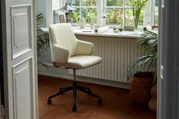 Stressless Laurel Home-Office-Stuhl in der Farbe Paloma Light Grey mit schwarzem Untergestell auf Rollen. Der Stuhl steht in einem hellen, gemütlichen Arbeitsbereich mit Pflanzen und einer großen Fensterfront.