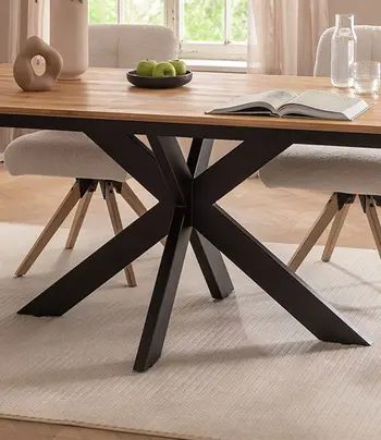 Sternförmiges Metallgestell eines hochwertigen Esstischs mit Massivholz Tischplatte.