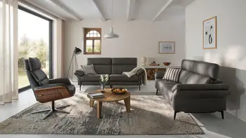 Minimalistisches Wohnzimmer mit zwei schwarzen Ledersofas und passendem Relaxsessel.