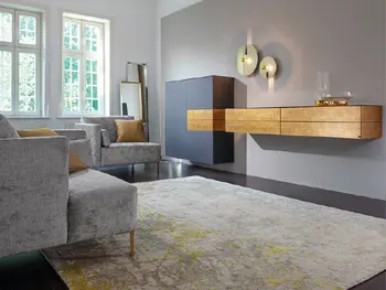 Designer Sideboard aus Holz hängt an einer Wand, daneben ein Schrank in Grau, der die Weiterführung des Sideboards mit aufnimmt.&nbsp;