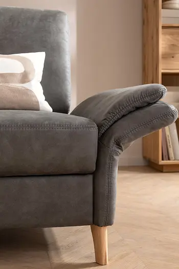 Detailbild einer klappbaren Armlehne eines grauen Ledersofas.