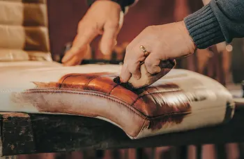 Person trägt mit einem Schwamm braune Farbe auf einen Stoff auf.