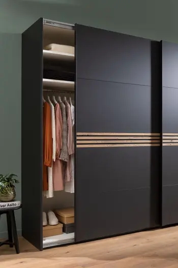 Schwarzer Schwebetürenschrank mit Akzenten in Holz in der Mitte der Türen.