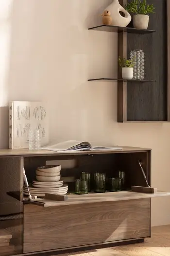 TV Board aus massiver Buche, bei dem ein Klappfach geöffnet ist und darin stehendes Geschirr sichtbar ist.