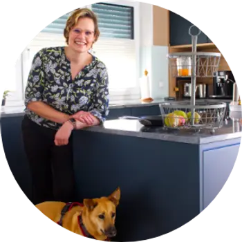 Frau in dunkelblauer Küche mit Hund