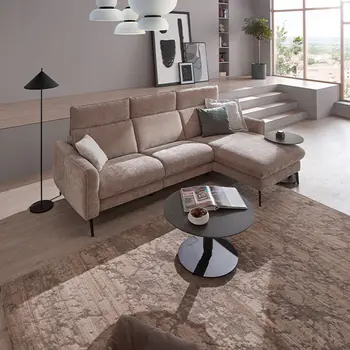 Beiges Ecksofa mit Stoffbezug, rundem Couchtisch und großem beigen Teppich in hellem Wohnzimmer.