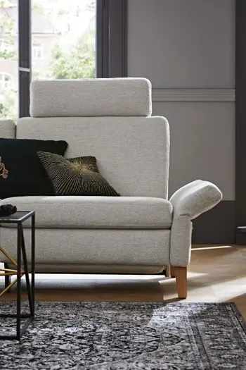 Rechter Teil eines grauen Sofas, das mit Stoff bezogen ist und eine Kopfstütze hat.