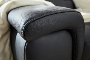 Armlehne eines schwarzen Ledersofas.