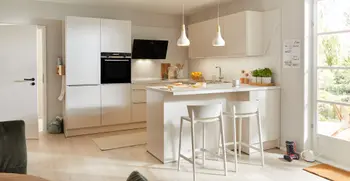 Weiße Küche mit Kücheninsel und Tresen mit Hockern.