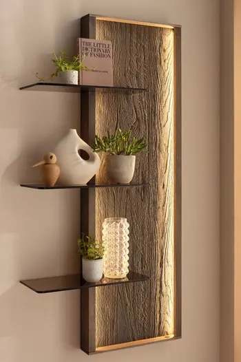 Modernes Wandregal in braun mit indirekter Beleuchtung und drei Regalböden aus dunklem Glas, dekoriert mit Vasen und Blumentöpfen in beigetönen.