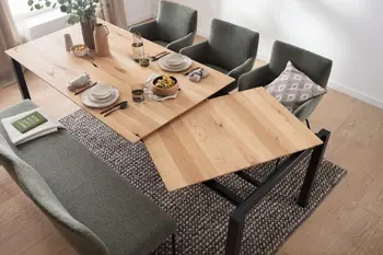 Esstisch aus Eiche Massivholz, bei dem gerade die Ausziehplatte unter dem Tisch herausgezogen wird für einen großen Esstisch.