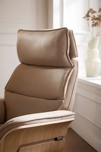 Beiger Design Relaxsessel mit Holzschale an der Armlehne, bei dem das Kopfteil nach vorne geneigt ist.