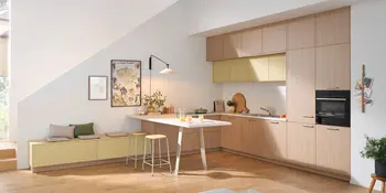 Wohnküche mit Holzfronten, gelben Hängeschränken und Frühstückstresen, Global Küchen.