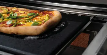 Frisch gebackene Pizza auf Backschiene einer Flammkraft-Outdoorkueche. 