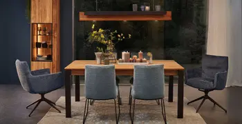 Polsterstuhl mit Armlehne und ohne Armlehne mit schwarzem Gestell an einem modernem Esszimmertisch aus Holz vor einem großen Fenster.