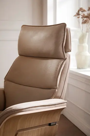 Beiger Design Relaxsessel aus Leder mit heller Holzschale an den Armlehnen und verstellbarem Kopfteil.