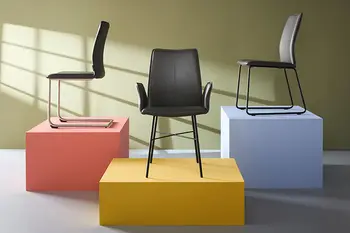 Freischwinger mit silbernem Gestell neben einem Armlehnstuhl und Esszimmerstuhl mit schwarzem Gestell. 