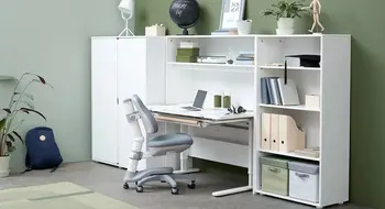 Ein Junge sitzt auf der oberen Bettes eines Etagenbetts in einem gemütlichen Innenraum mit sichtbaren Möbeln und einem Fernseher.