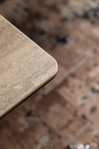 Ecke eines beigen Keramik Couchtisches.