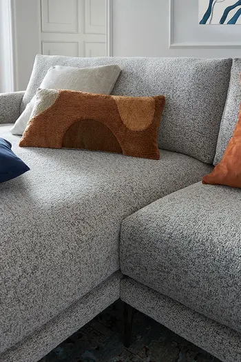 Graues Design Ecksofa mit mehreren Kissen. 