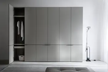 Moderner grauer Kleiderschrank mit sechs Türen, bei dem die erste Türe offen steht und Einblick auf eine Kleiderstange mit Blusen, ein Regalboden und ein Fach freigibt.