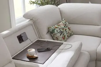 Beiges Sofa, bei dem eine Rückenlehne komplett nach vorne geklappt ist und die Sicht auf eine in der Rückenlehne integrierte Steckdose und USB-Anschluss freigibt. 