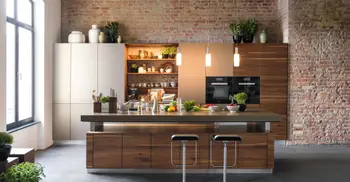 Massivholzküche mit vielen Lebensmitteln/Zutaten auf der Arbeitsplatte. Im Hintergrund ein Ziegelgemäuer.