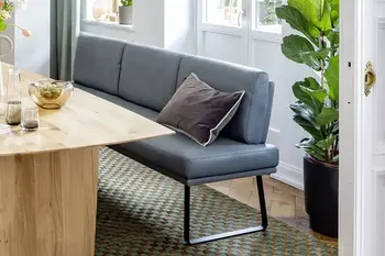 Blaue Esszimmerbank mit schwarzem Metallgestell in einem hellen Esszimmer an einem hellen Massivholzesstisch.