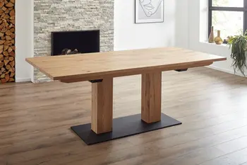 Massivholz Esstisch mit zwei dicken Holzbeinen, die auf einer schwarzen Metallplatte stehen.