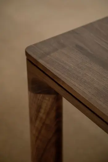 Ansicht von oben auf eine abgerundete Ecke eines Esszimmertisches aus Nussbaum Holz.