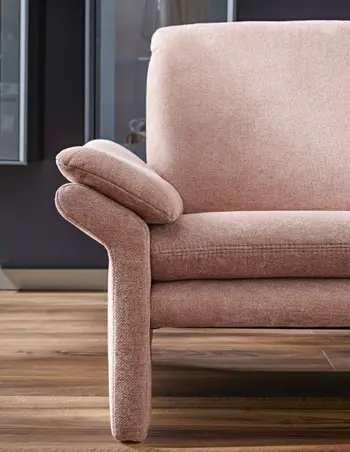 Rosanes Sofa, das an der Armlehne ein kleines zusätzliches Kissen hat.