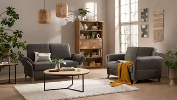 Gemütliches Wohnzimmer mit zwei Zweisitzer-Sofas in dunklem Grün, rundem Couchtisch und Regal aus Massivholz.