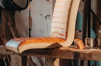 Braune Sitzfläche eines Stuhls, der gerade gebaut wird und auf einer Holzbank steht aber noch ohne Fußgestell ist.