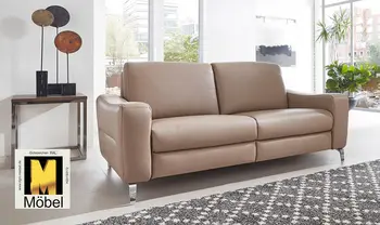 Beiges Ledersofa mit silbernen Kufen und dem Goldenen M Logo im Bild.