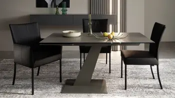 Modernes Esszimmer mit drei schwarzen Stühlen, einer mit und zwei ohne Armlehne und schwarzem Fußgestell um einen kleinen Esstisch mit schwarzer Tischplatte.