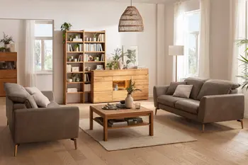 Zwei gegenüber stehende Sofas in braugrauem Leder, dazwischen ein quadratischer Couchtisch aus Holz in einem gemütlich eingerichteten Wohnzimmer.