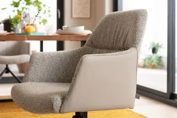 Grauer Armlehnstuhl, der außen mit Leder und innen mit Stoff bezogen ist.