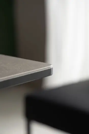 Tischkante eines modernen Esstisches mit schwarzer Tischplatte aus der Nähe.