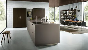 Moderne offene Wohnküche mit Kochinsel, dunklem Essbereich, Bücherregal und großflächigen Fenstern mit Blick ins Grüne