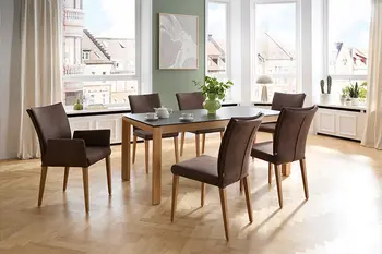 Klassisches Esszimmer mit großem Esstisch und sechs Stühlen mit braunem Stoff und Holzbeinen.