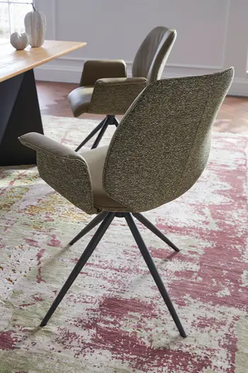 Grüner Design Schalenstuhl mit schwarzem Gestell an einem Esstisch.